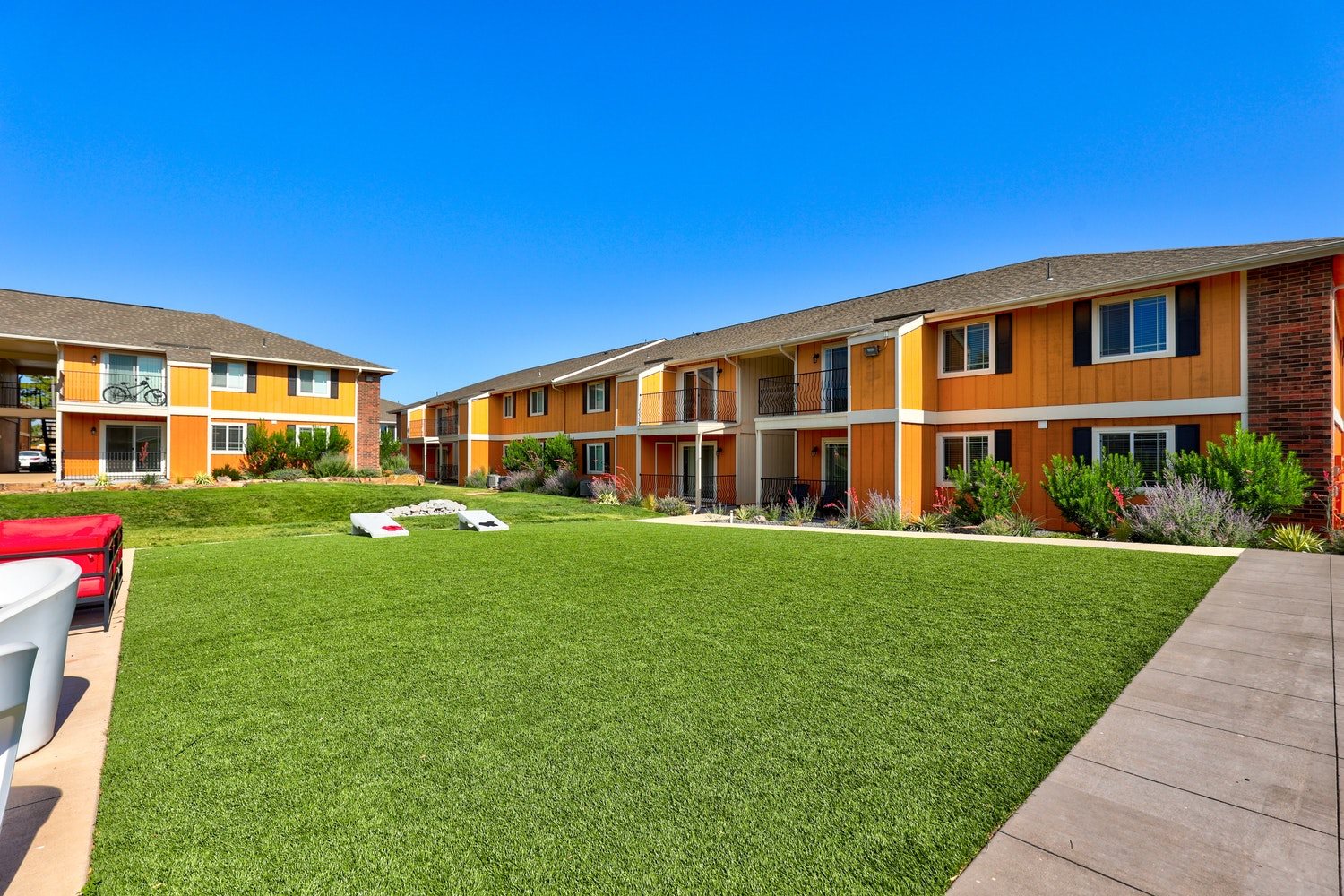 A sunny day at a residential complex with green lawns and orange buildings.